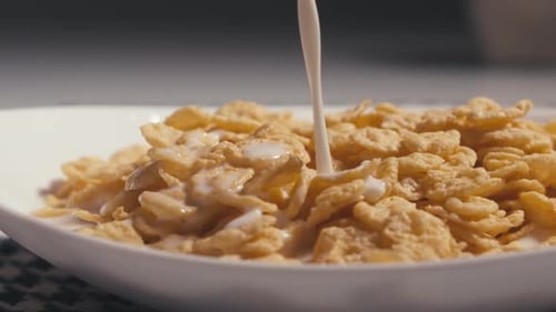 Golden Cornflakes with Milk Being Poured Close Up