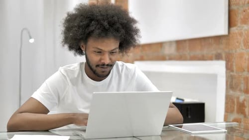 Young Man Typing on Laptop in Office