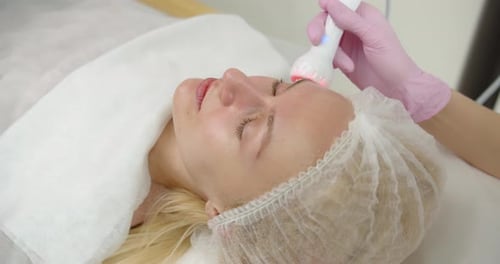 Arzt führt kosmetische Eingriffe in einem Schönheitssalon auf dem Gesicht einer jungen Frau durch