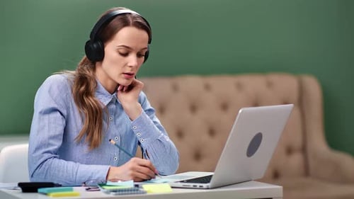 Woman Works at Home with Laptop and Headphones