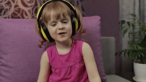 Child with Headphones Listens and Dances to Music