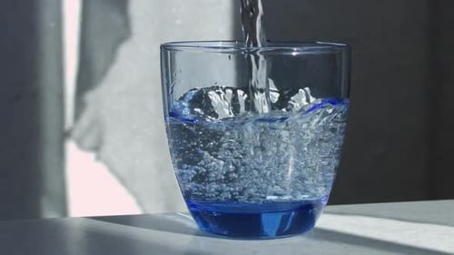 Clear Water Being Poured into a Blue Glass
