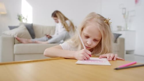 Blonde Girl Drawing at Table with Mother