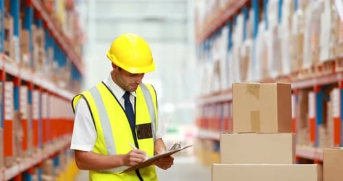 Male warehouse worker writing on clipboard