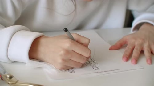 Fashion Designer Drawing on Paper with Pen