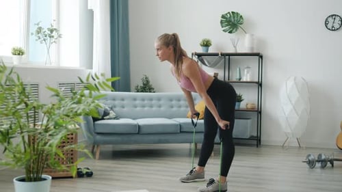 Woman Exercises with Resistance Band in Bright Living Room