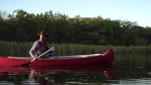 Cowboy in a Canoe Floats on the River