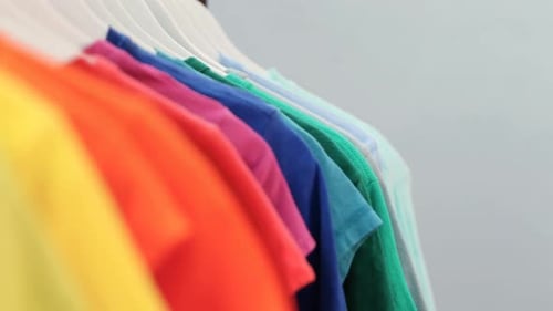 Various t-shirts arranged in a row on cloth rack 4k