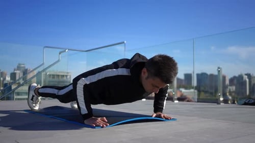 Junger Sportler aus dem Nahen Osten macht Liegestütze beim Training auf dem Dach mit Blick auf Kiew Ukraine bei