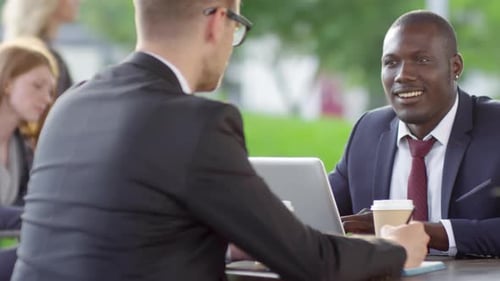 Businessmen Discussing Work in Outdoor Cafe