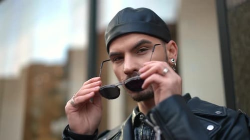 Young Adult Puts on Sunglasses in City