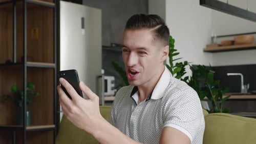 Excited man celebrating success while looking at phone