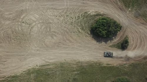 Military Tank Driving Across Sandy Rural Landscape