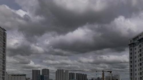 Time lapse of fast moving storm clouds moving from right to left across the sky and high rise buildi