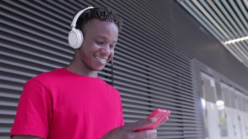 Happy Young African Man Using Mobile Phone in the Street