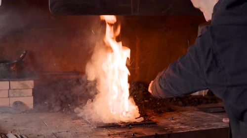 Blacksmith Adjusting Metal in Fiery Hot Forge