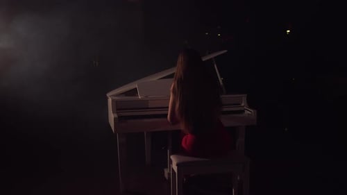 Woman Plays Piano in Dramatic Spotlight Setting