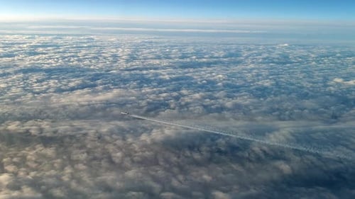Incredible view from the cockpit of an airplane flying high above the clouds leaving a long white co