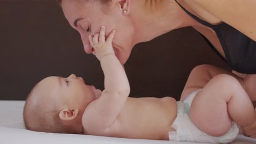 Nahaufnahme. Mutter küsst Baby sanft und genießt liebevolle Mutter, die sich spielerisch um das Kleinkind zu Hause kümmert