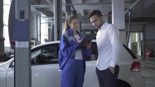 Female Automobile Specialist Taking Datas About Car for Inspection By Young Attractive Man in Car