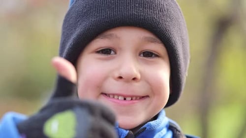 Smiling Child Giving Thumbs Up Outdoors in Autumn