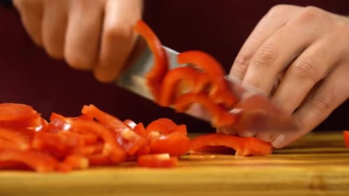 Close view man's hand cutting red pepper.