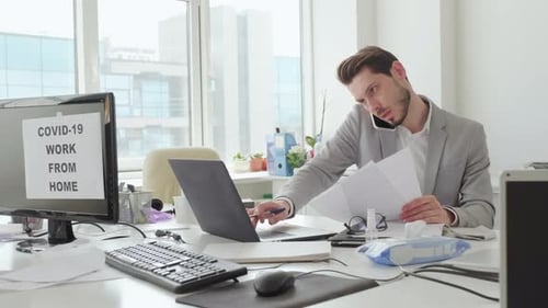 Businessman Talking on Mobile Phone and Working with Documents in Office