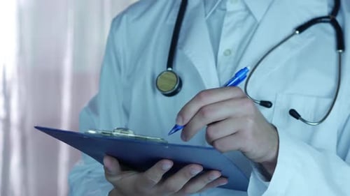 Doctor Writing on Clipboard Wearing a White Coat
