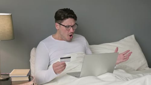 Man in Bed Frustrated with Online Transaction