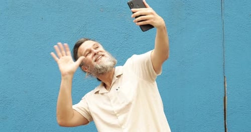 Man Taking Selfie Against a Blue Wall