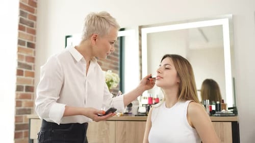 Makeup Artist Applying Powder to Model in Studio