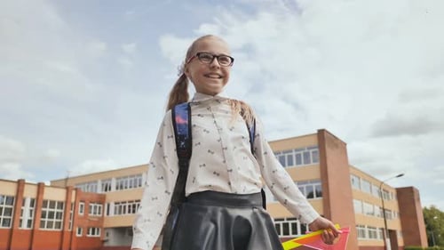 Feliz colegiala de once años corre con una mochila y libros de ejercicios después de la escuela.