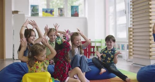 Storytime Elementary or Primary School Teacher Reading a Story to a Group of Children in a Daycare