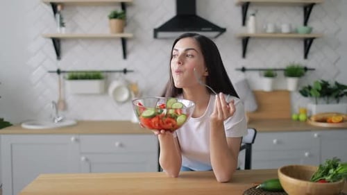 Woman Enjoys Fresh Salad in Bright Kitchen
