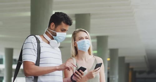 Young Man and Woman in Masks Holding Phones
