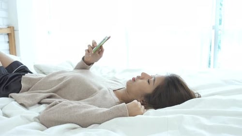 Woman Relaxing in Bed Using Mobile Phone