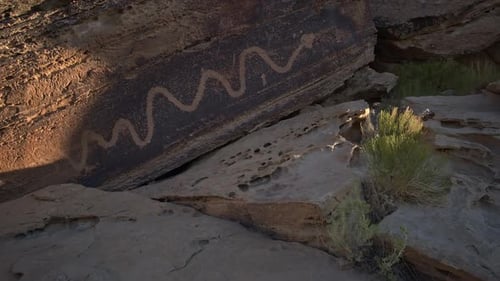 Snake petroglyph in the Utah desert on boulder at base of cliffs