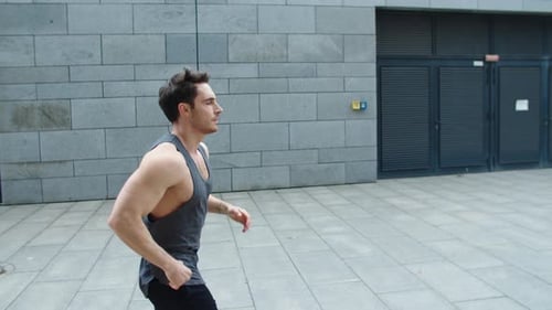 Sporty Man Running Outdoor. Male Runner Jogging on City Street in Slow Motion.