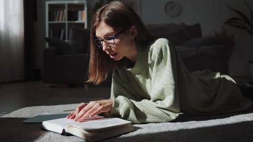 Woman Reads Book and Takes Notes on Floor