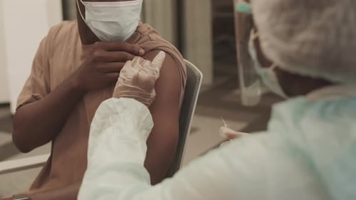 Health Professional Administering Injection To Young Adult