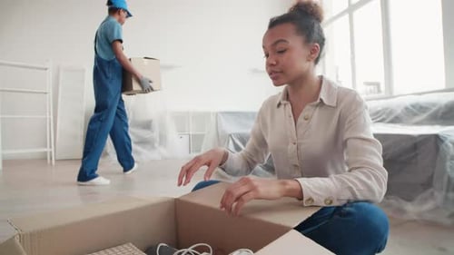 Woman Unpacking Cardboard Box Moving into New Home
