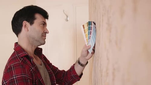 Man Comparing Paint Swatches on Wall Indoors