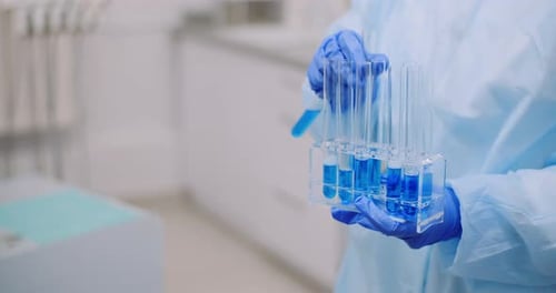 Researcher Handling Test Tubes with Blue Liquid in Lab