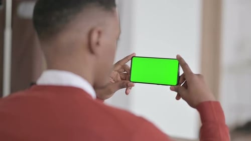 Rear View of African Man Holding Smartphone with Green Chroma Screen
