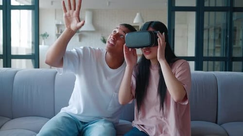 Couple uses VR headset sitting on couch indoors
