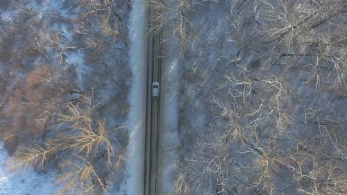 Above View of White SUV Going on a Snow Covered Forest Road