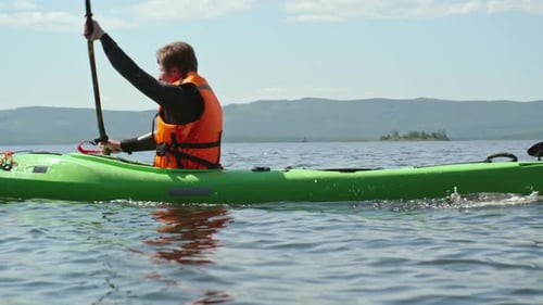 Man Paddling a Kayak on a Sunny Lake