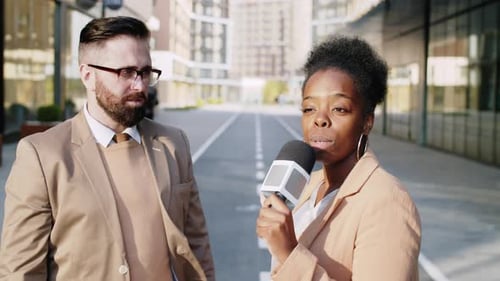 Reporter Interviews Man on City Street with Microphone