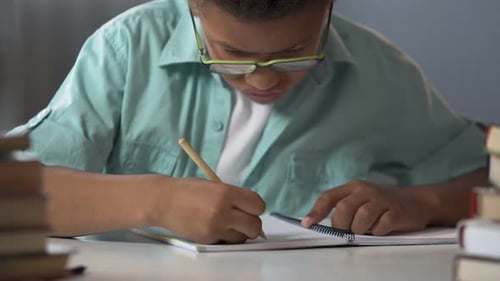 First-Grader Boy Carefully Writing Letters in His Copybook, Doing Homework