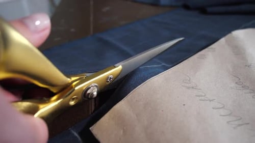 Finger der Schneiderin, die Stoff und Schere hält